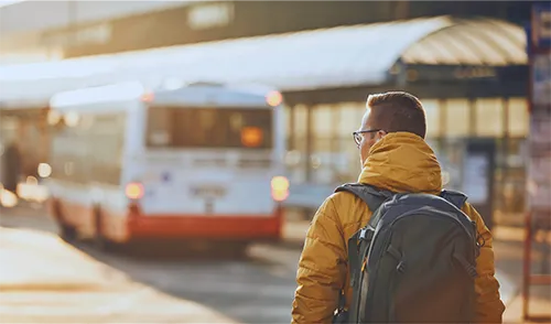 Bus rider with backpack in from of bus
