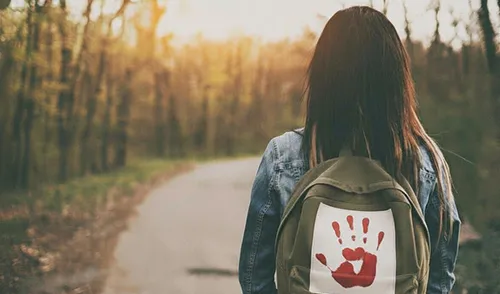 Women with back that contains a missing and murdered indigenous women hand print walking on a path