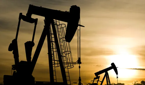 Oil derrick in front of sun
